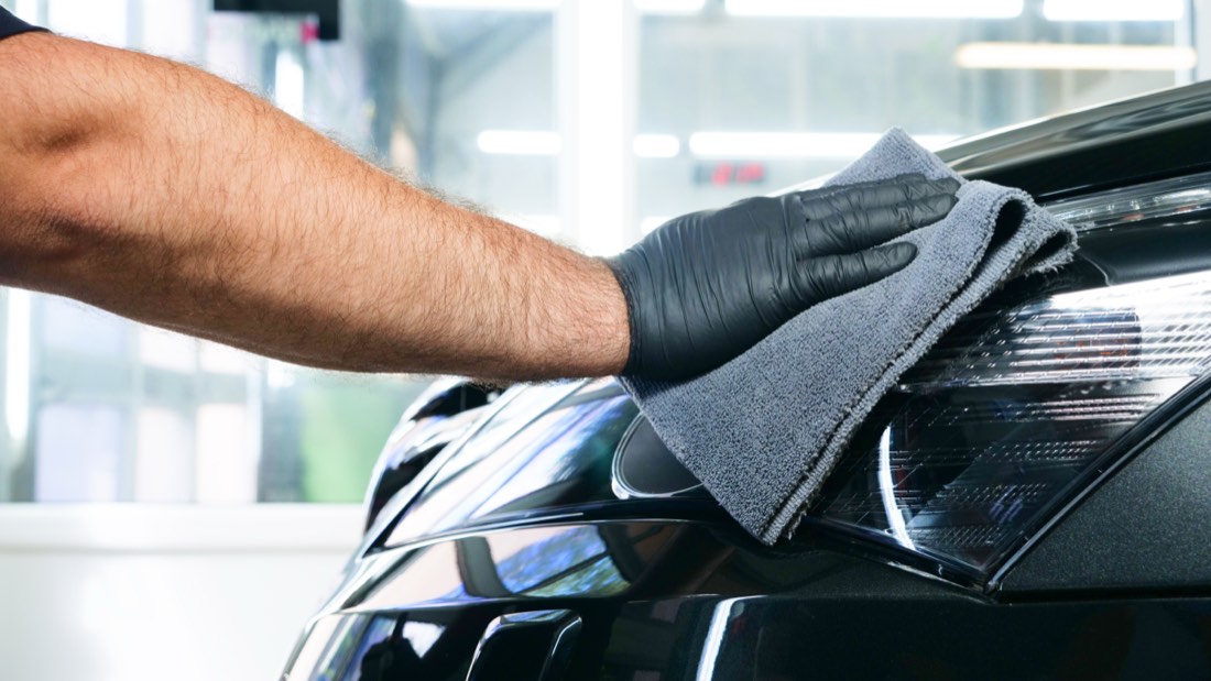 Two detailers drying a car after washing
