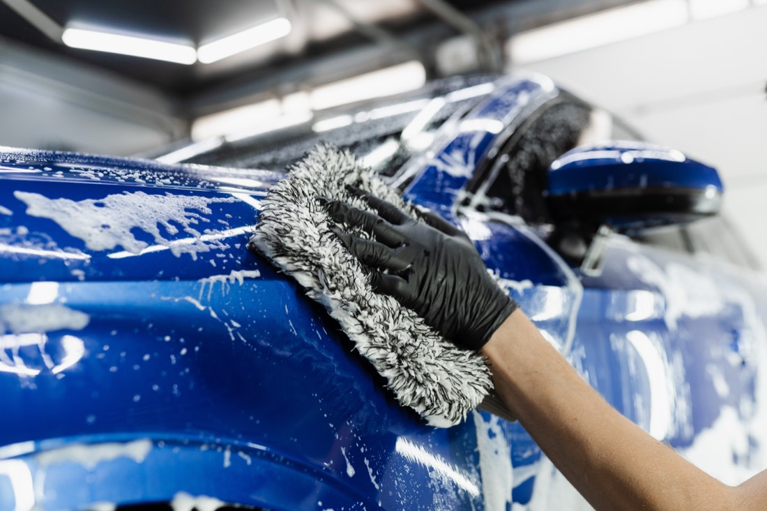 Hand washing a car body with foam and a microfiber glove