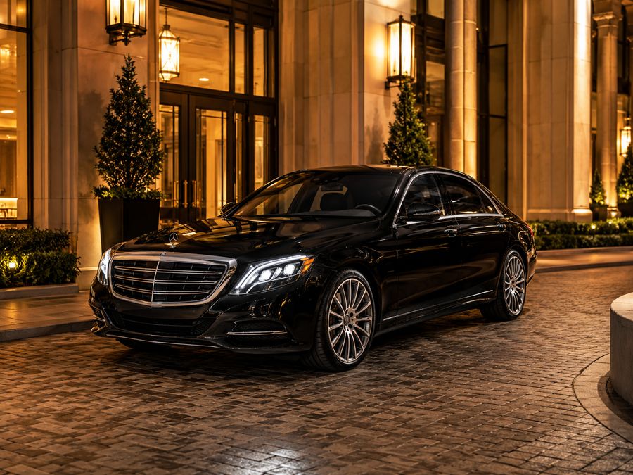 Black luxury sedan parked outside a hotel entrance