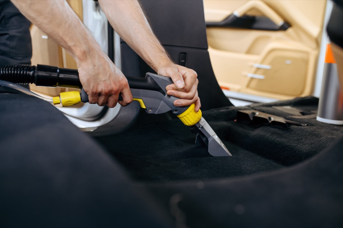 Worker vacuuming a car interior