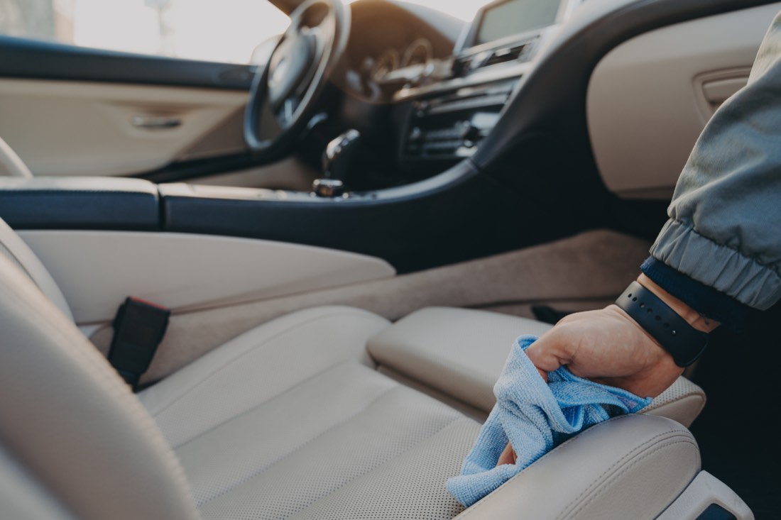 Detailer wiping a car interior with a microfiber cloth